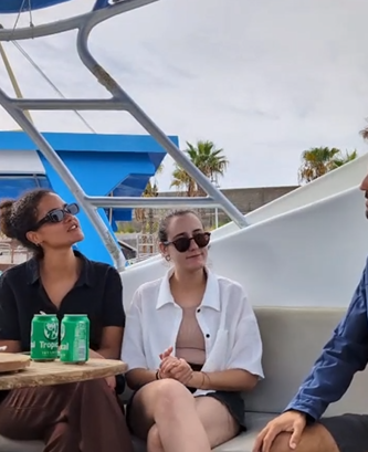 Delfines La Palma People sitting on a boat with drinks, talking under a partly cloudy sky.